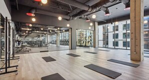 A gym with exercise equipment, mats, and a large window. - Landing | Chic 1BD, Pool, Gym (Nashville)