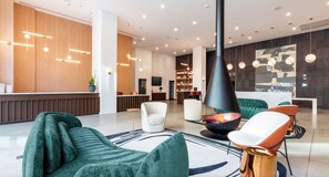 A modern lobby with a reception desk, seating area, and a fireplace. - Landing | Stunning 2BD, Pool, Gym (Nashville)