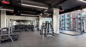 A gym with weightlifting equipment, benches, and a mirrored wall. - Landing | Stunning 1BD, Pool, Gym (Nashville)