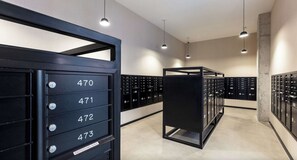A modern mailroom with numbered mailboxes and a central sorting area. - Landing | Amazing Studio, Gym, Pool (Nashville)