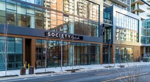 A modern building with large glass windows and a sign that reads 'SOCIETY Nashville.' - Landing | Chic 1BD, Pool, Gym (Nashville)
