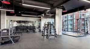 A gym with various weightlifting equipment, a squat rack, and a bench. - Landing | Stylish 1BD, Gym, Pool (Nashville)