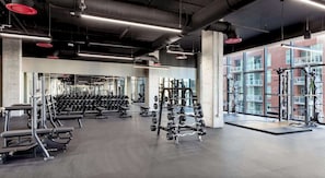 A gym with various weightlifting equipment, a squat rack, and a bench. - Landing | Stunning 1BD, Gym, Pool (Nashville)