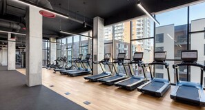 A gym with treadmills and exercise equipment, large windows, and a modern industrial design. - Landing | Beautiful Studio, Pool, Gym (Nashville)
