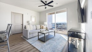 A modern living room with a sofa, coffee table, and a TV on a stand. - Landing | Modern 2BD, Game Room, Clubhouse (Littleton)