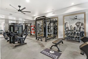 A gym with various exercise equipment, including weight machines and free weights, and a mirror wall. - Landing | Modern 2BD, Game Room, Clubhouse (Littleton)