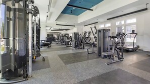 A modern gym with various exercise equipment, large windows, and a high ceiling. - Landing | Chic 1BD in Whitestone (Fort Worth)