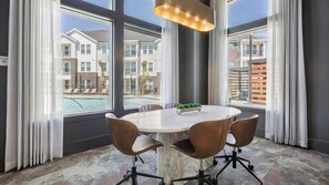 A conference room with a round table, four chairs, a potted plant, and large windows with a view of a pool and buildings. - Landing | Incredible 1BD in Whitestone (Fort Worth)