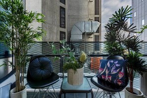 A balcony with two chairs, a table, and potted plants. - Stylish 2 Bedroom in Southbank (Southbank)