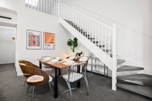A dining area with a staircase, a table set for four, and two chairs. - Unique Southbank Loft (Southbank)