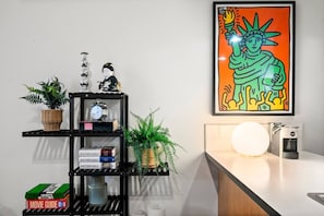 A modern kitchen with a black shelving unit, a coffee machine, and a framed artwork of the Statue of Liberty. - Unique Southbank Loft (Southbank)
