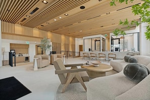 A modern interior with a wooden ceiling, a reception desk, seating area, and a large window. - Landing | Modern 2BD in North Burnet (Austin)
