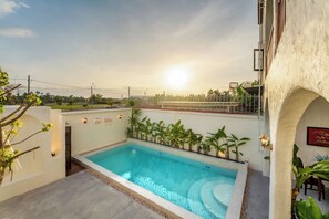 A swimming pool with a view of the sunset, surrounded by greenery and a white building. - Hidden 5BR Pool Villa - 8' Walk to An Bang Beach (Đà Nẵng)