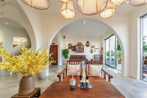 A spacious room with a wooden dining table, chairs, and a large window. - Hidden 5BR Pool Villa - 8' Walk to An Bang Beach (Đà Nẵng)