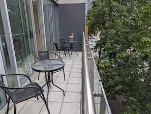 A balcony with outdoor seating, glass doors, and a view of a tree. - 2 Bedroom near Crown, Sleeps 6 (Southbank)