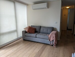 A room with a grey sofa, a brown pillow, a pink blanket, and a wooden floor. - 2 Bedroom near Crown, Sleeps 6 (Southbank)