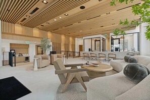 A modern interior with a wooden ceiling, a reception desk, seating area, and a large window. - Landing | Amazing 1BD in North Burnet (Austin)
