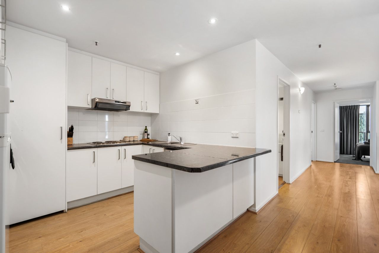 A modern kitchen with white cabinets, a central island, and wooden flooring.