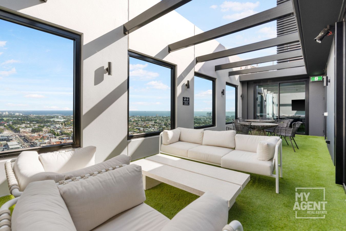 A modern office space with a large window offering a city view, a white sofa, and a small table.