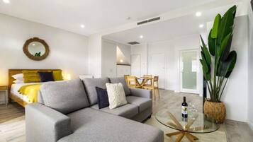 A modern living room with a grey sofa, a round coffee table, and a dining area with a wooden table and chairs.