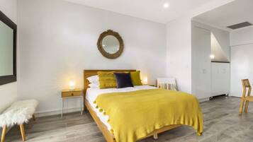 A modern bedroom with a bed, bedside tables, a mirror, and a wardrobe.