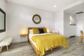 Ein modernes Schlafzimmer mit Bett, Nachttischen, einem Spiegel und einem Kleiderschrank.