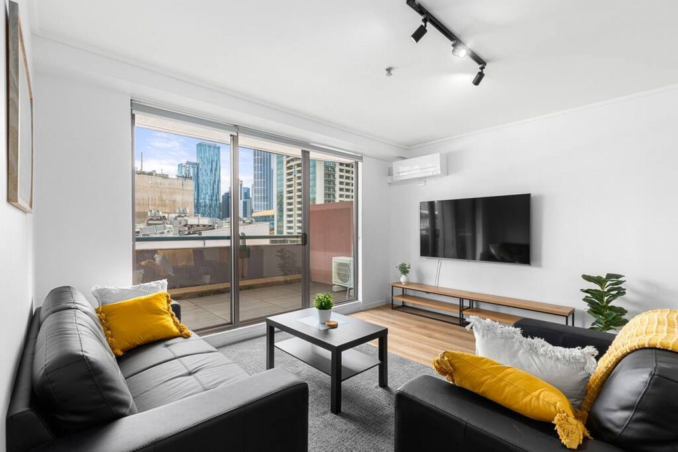 A modern living room with a sofa, coffee table, and a flat-screen TV mounted on the wall.