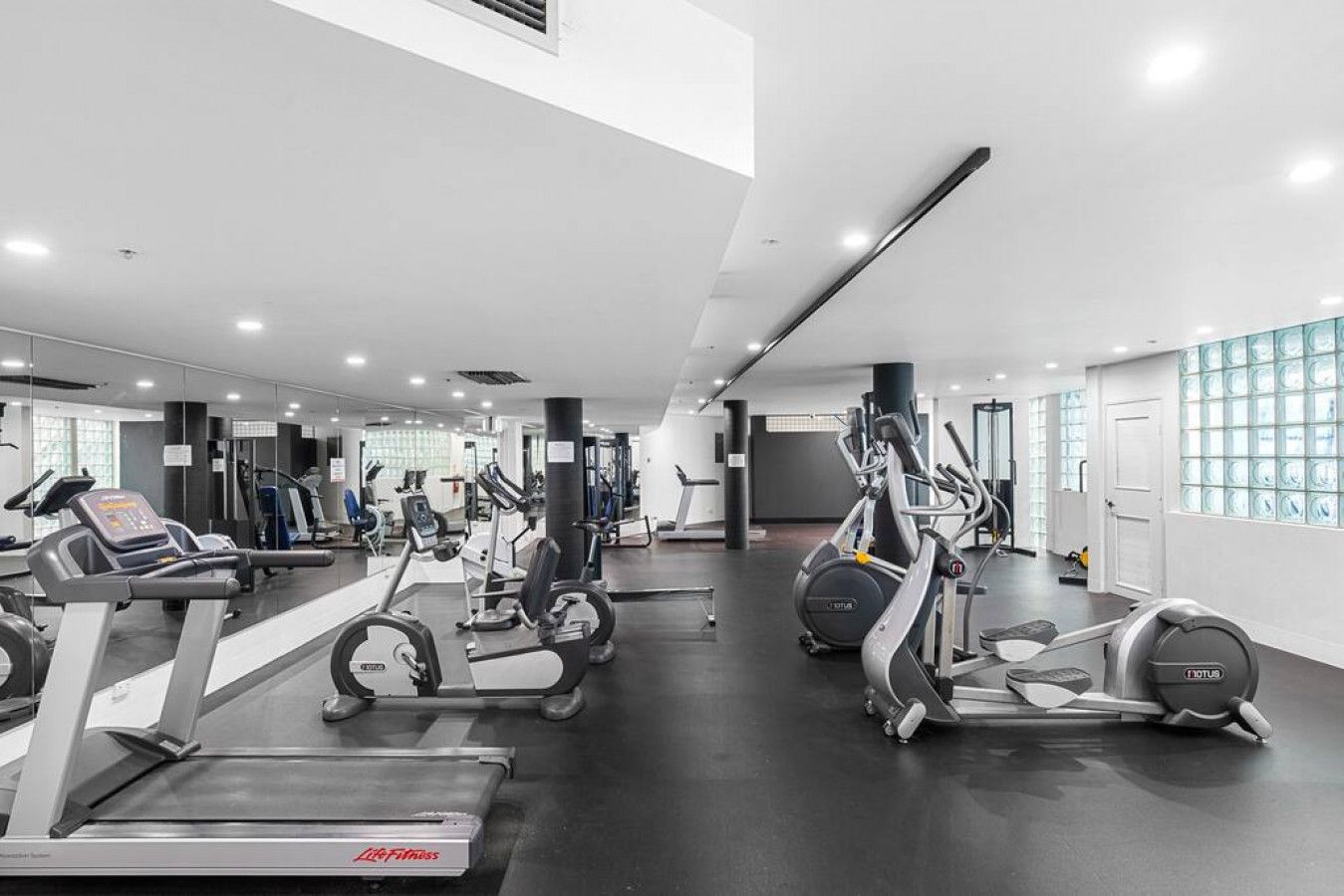 A gym with cardio machines, weight stations, and mirrors on the walls.