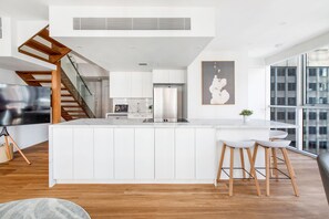 Eine moderne Küche mit weißen Schränken, einem Edelstahlkühlschrank und einer zentralen Kochinsel mit Sitzgelegenheiten.
