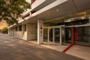A modern building entrance with a glass door, a ramp, and the letters 'CVL' on the wall. - Bay View 2 Bedroom Apartment (Port Melbourne)