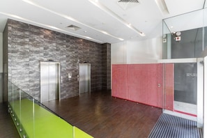 A modern lobby with two elevators, a glass railing, and a red safety barrier. - Bay View 2 Bedroom Apartment (Port Melbourne)