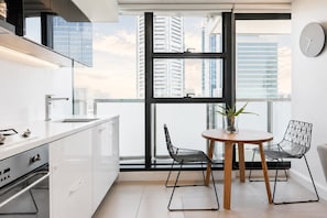 Cozinha moderna com área de refeições, janelas amplas e vista para a cidade.