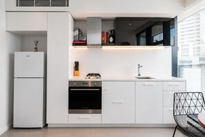 A modern kitchen with a built-in oven, a refrigerator, and a gas stove. - Level 24 City 1 Bedroom (Melbourne)