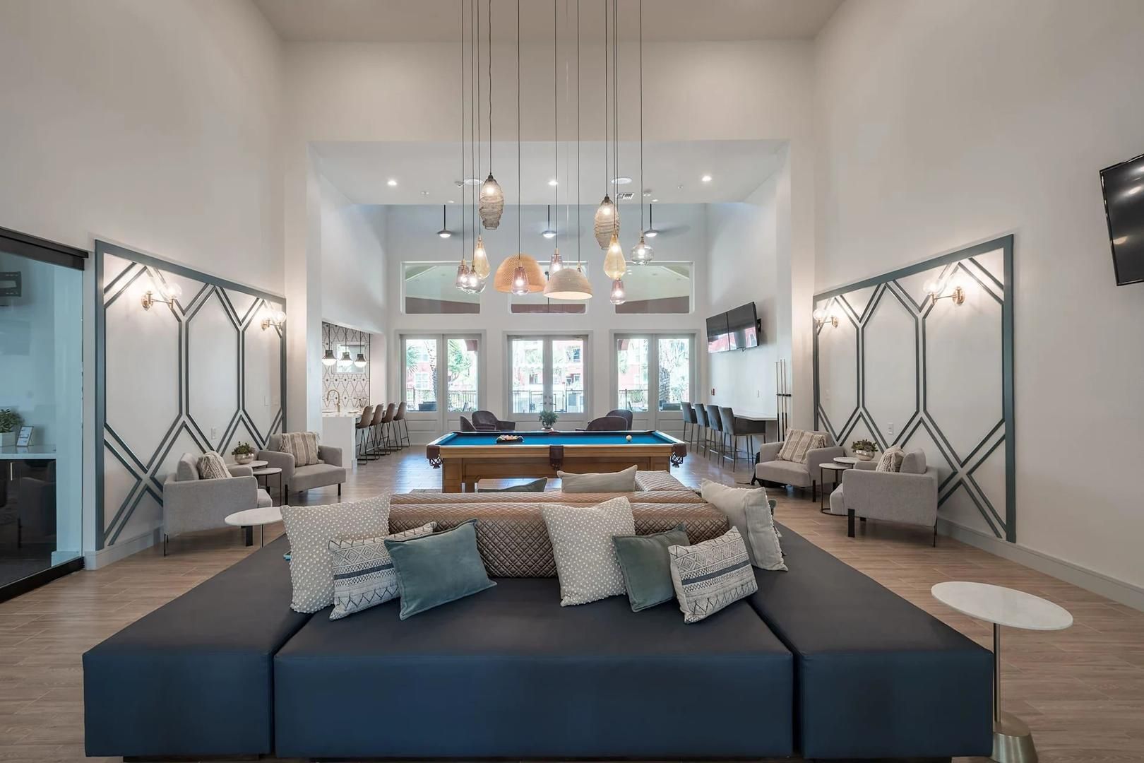 A spacious living area with a pool table, comfortable seating, and a large window providing natural light.