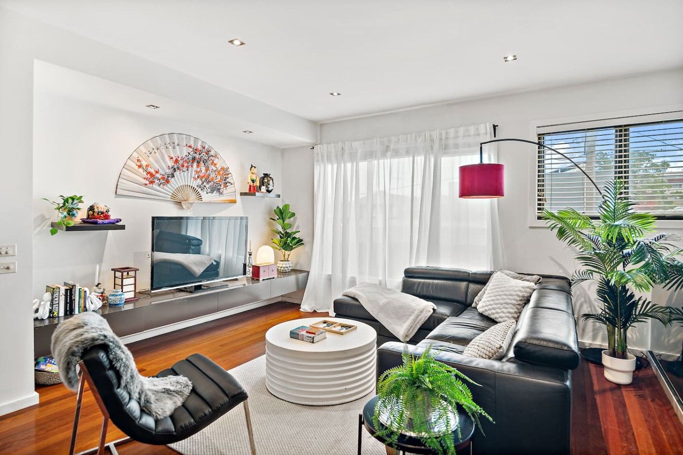 A modern living room with a sofa, a coffee table, a TV, and a decorative fan.