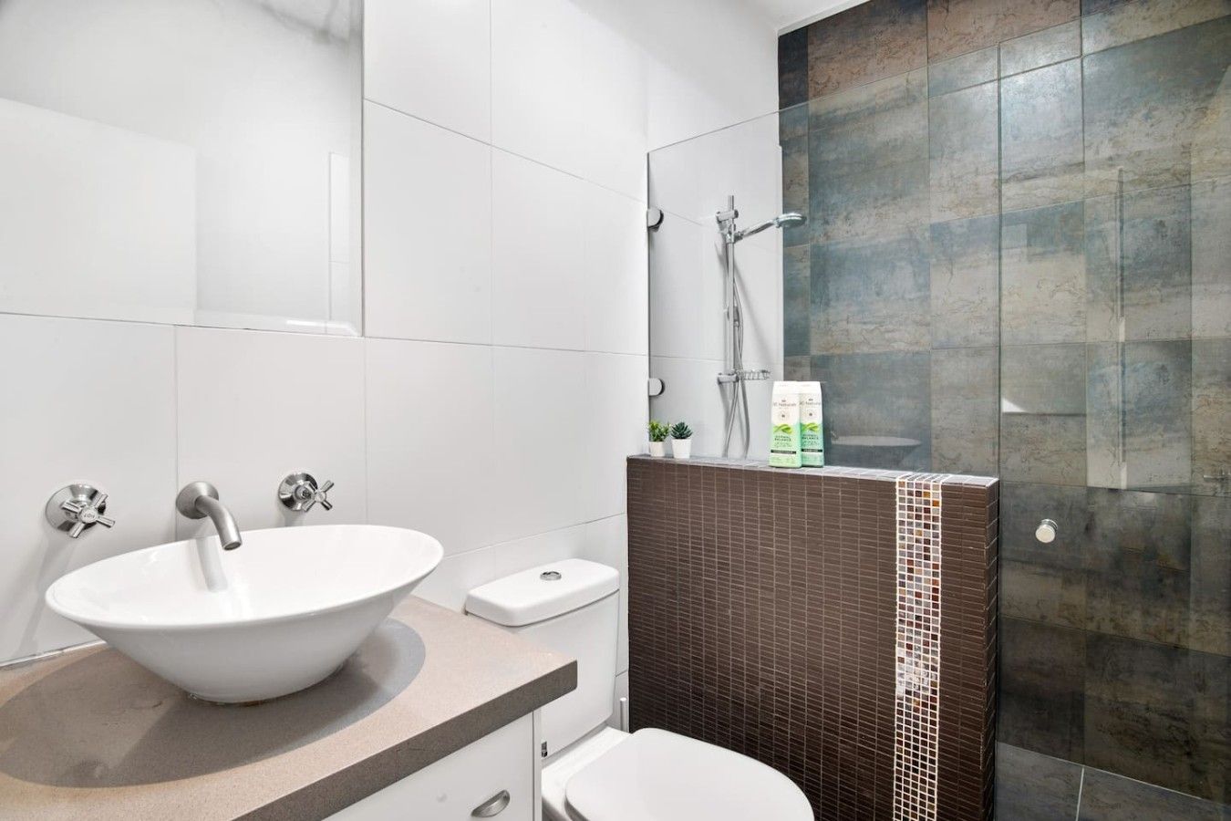 Ein modernes Badezimmer mit Waschbecken, Toilette und Duschbereich.