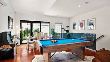 Una sala de estar moderna con mesa de billar, mesa de fútbol de mesa y comedor con sillas y una mesa.