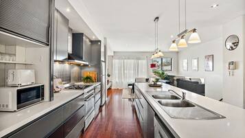A modern kitchen with stainless steel appliances, a central island, and pendant lighting.