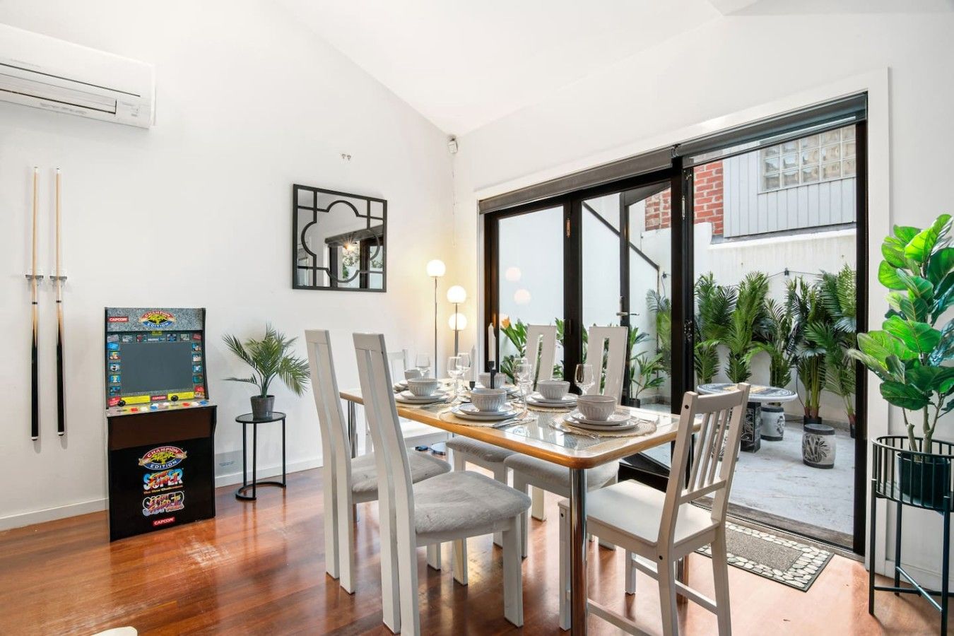 A dining area with a table set for four, a pool table, and a large window with a view of the outdoors.
