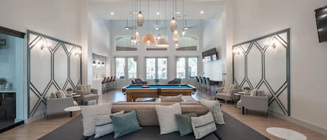 A spacious living area with a pool table, comfortable seating, and a large window providing natural light.