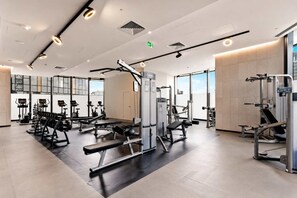 Een moderne sportschool met diverse fitnessapparaten, grote ramen en een schoon, goed verlicht interieur.