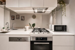 Een moderne keuken met een gasfornuis, magnetron, vaatwasser en spoelbak.