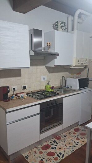 A compact kitchen with white cabinets, a gas stove, an oven, a microwave, and a sink. - Intero appartamento max 6 posti letto .
Fra Parma e Reggio Emilia (Sant'Ilario d'Enza)