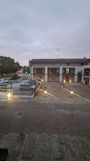 Un espace de stationnement avec plusieurs voitures et un bâtiment doté d’un toit plat et de nombreuses fenêtres.