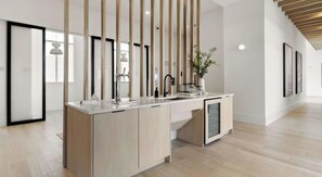 A modern kitchen with a central island, pendant lighting, and a view of the adjacent living area. - Landing | Spectacular 1BD in North Kissimmee (Kissimmee)