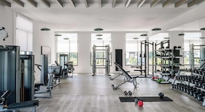 A spacious gym with various exercise equipment, large windows, and a high ceiling. - Landing | Beautiful 2BD in North Kissimmee (Kissimmee)
