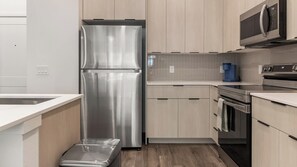 A modern kitchen with stainless steel appliances, wooden cabinets, and a tiled backsplash. - Landing | Beautiful 2BD in North Kissimmee (Kissimmee)