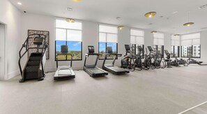 A gym with treadmills, elliptical machines, and a stair climber. - Landing | Modern 2BD in North Kissimmee (Kissimmee)