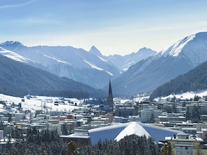 A town with a prominent church spire, surrounded by snow-covered mountains. - Jakobshorn by Interhome (Davos)