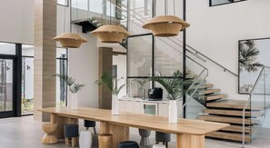 A modern interior with a wooden dining table, hanging light fixtures, and a staircase. - Landing | Stylish 2BD in North Kissimmee (Kissimmee)